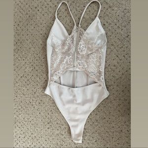 Slightly stretchy white bodysuit (one-piece). Mostly white, lace is off-white.